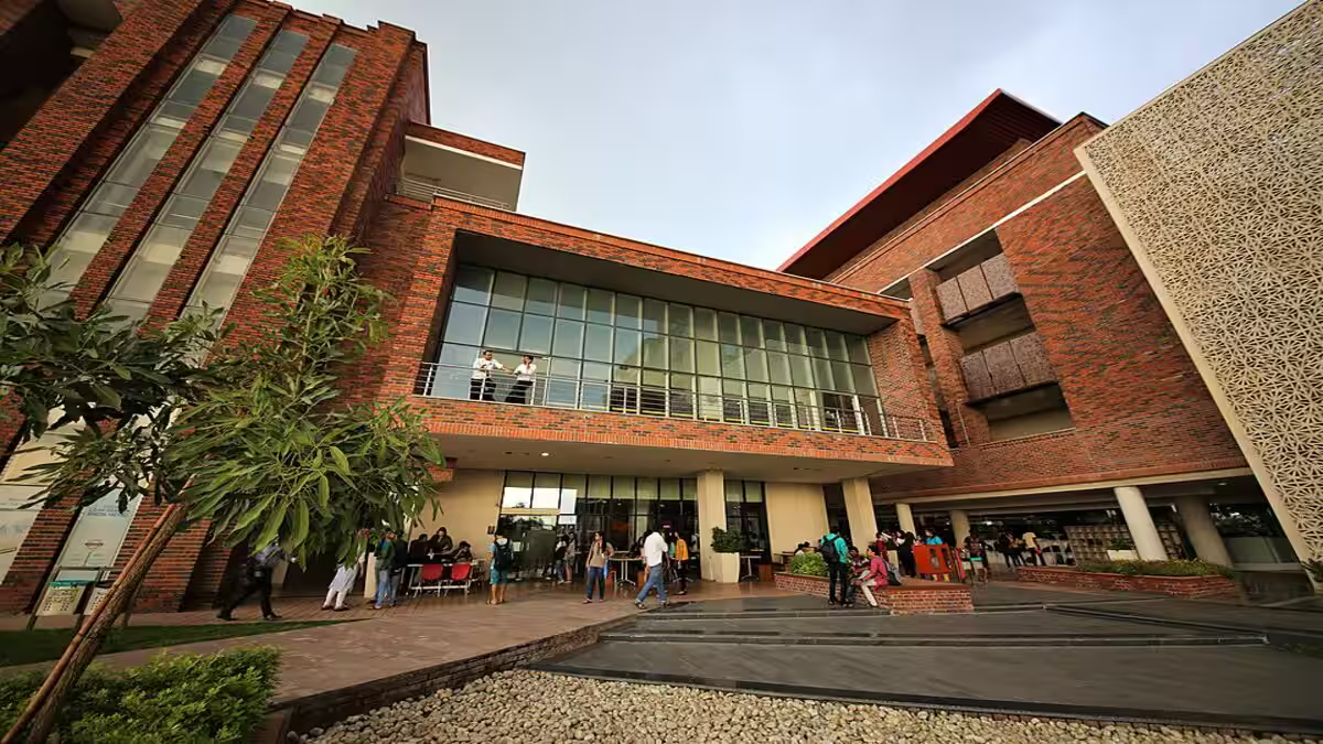 Ashoka University students gather outside modern brick building, some discussing politics.