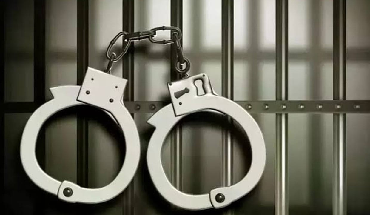 Handcuffs in front of jail bars, symbolizing arrest in US visa fraud case.
