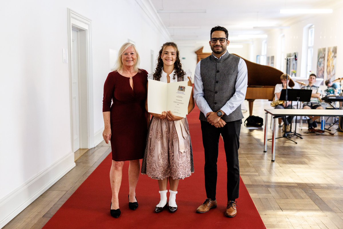 Bavarian Ambassador Program: Woman and man with certificate, girl in traditional dress.