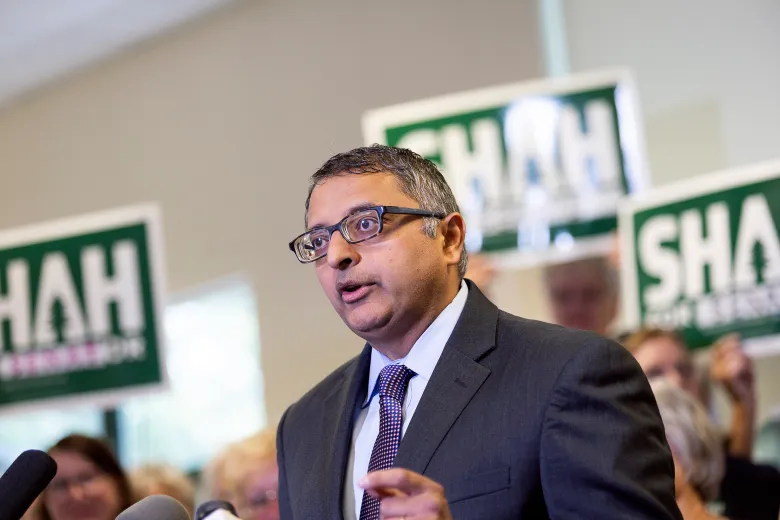 Nirav Shah speaking at press conference with Maine Senate signs in background