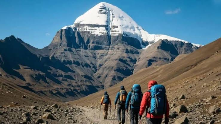 Hikers with backpacks ascend a mountain trail towards Mount Kailash, raising travel safety concerns.