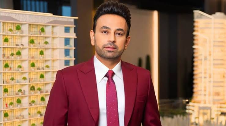 Indian businessman Satish Sanpal in a suit, with buildings in the background.