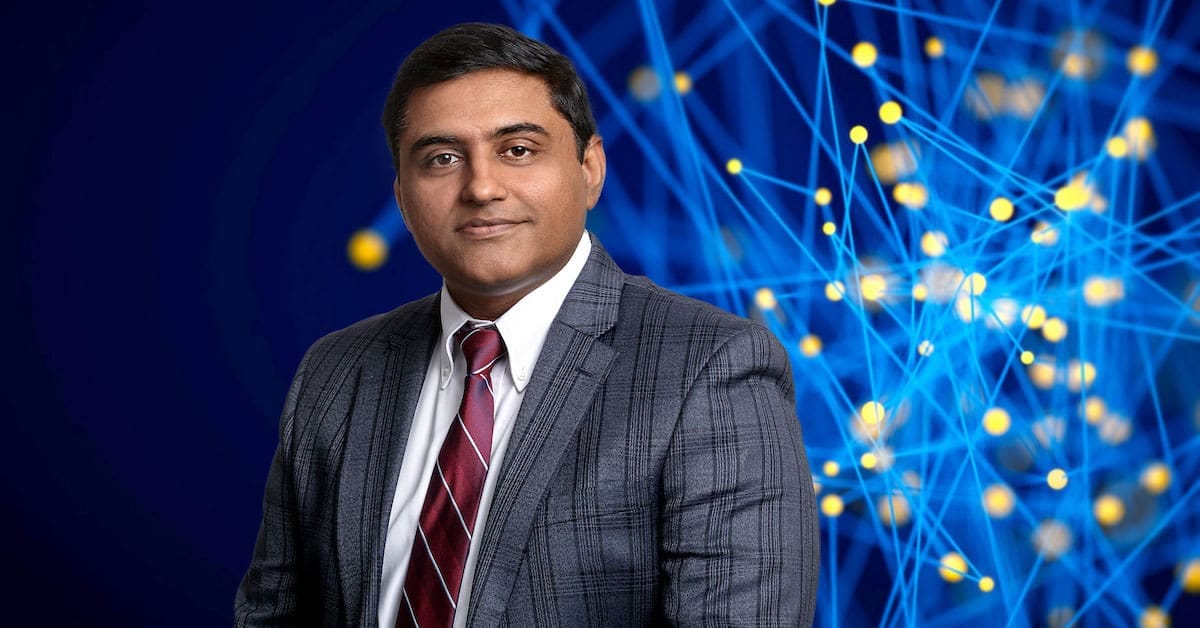 Indian American professor in suit with AI tech background