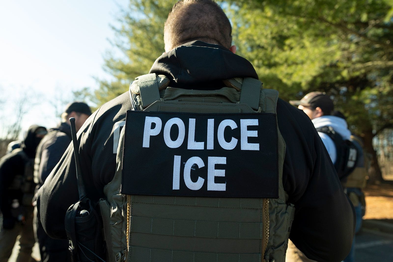 ICE agent in tactical vest with "POLICE ICE" patch, immigration enforcement.