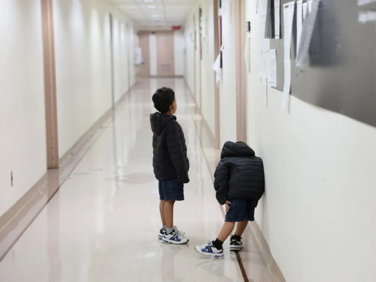 Two young children in a hallway, their faces obscured, reflecting deportation fears for migrant kids.