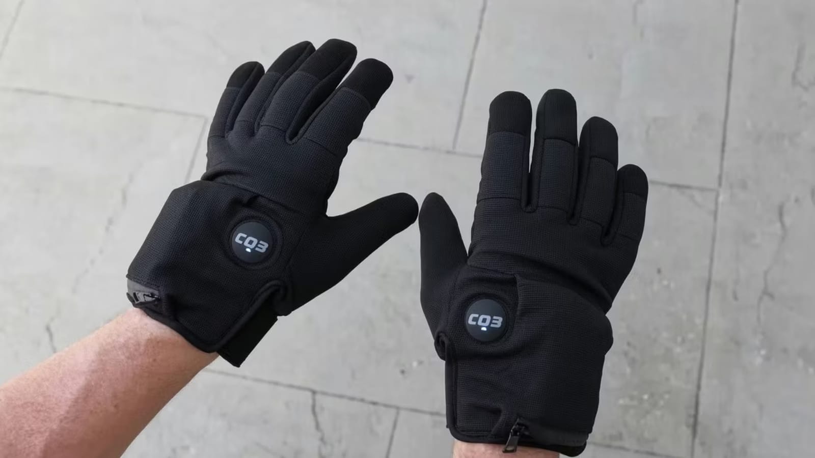 Black CQ3 electric shock gloves on hands, sparking misuse concerns.