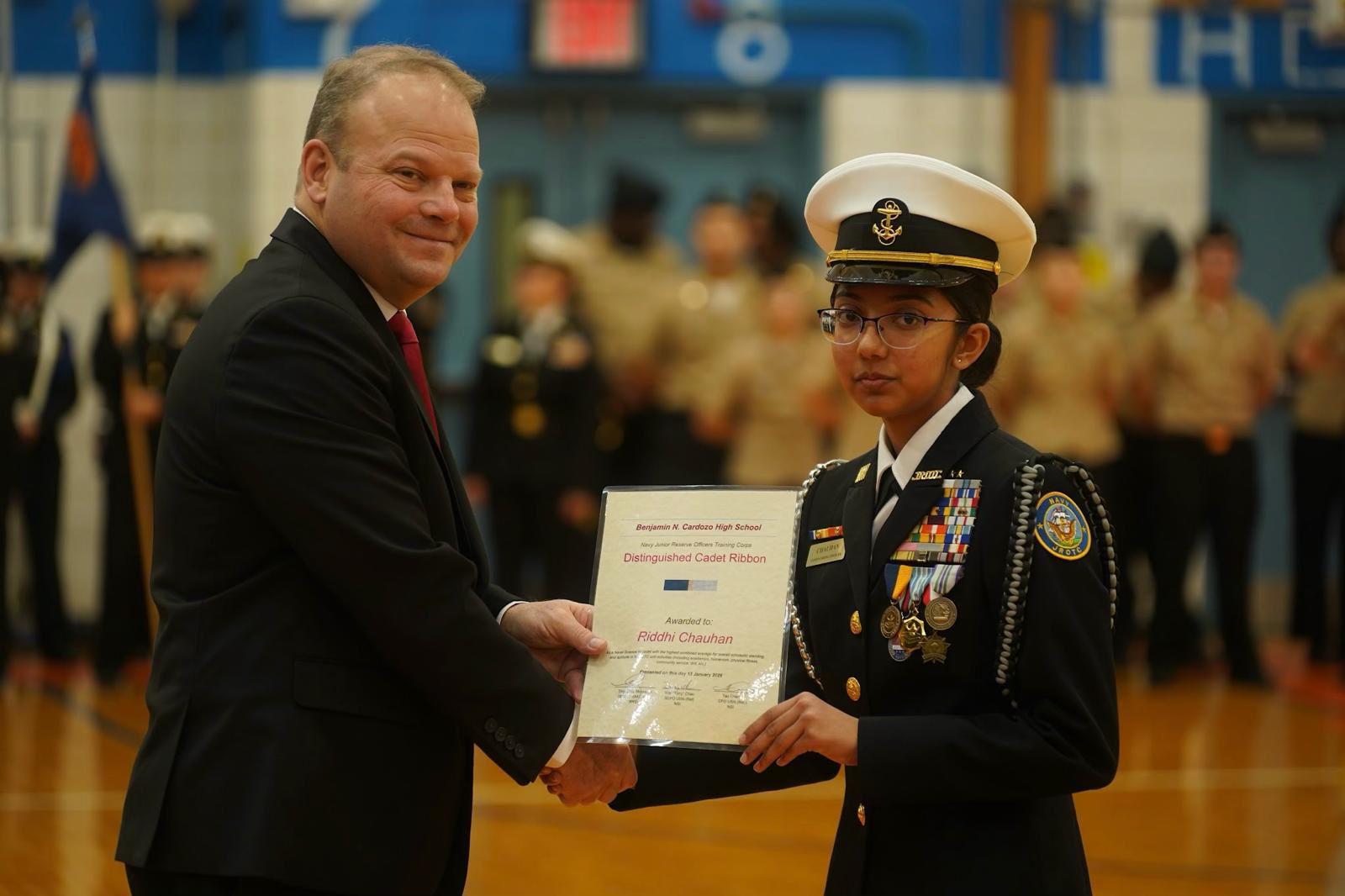 Riddhi Chauhan receives Distinguished Cadet Ribbon from school official at Benjamin N. Cardozo High School NJROTC event.