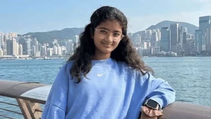 Young Indian-origin girl in blue sweatshirt, a tech innovator.