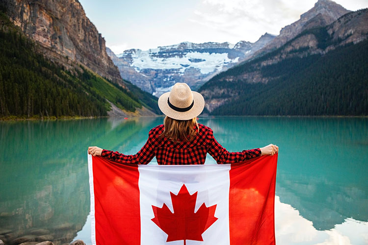 Woman with Canadian flag overlooking Lake Louise, Alberta, Canada