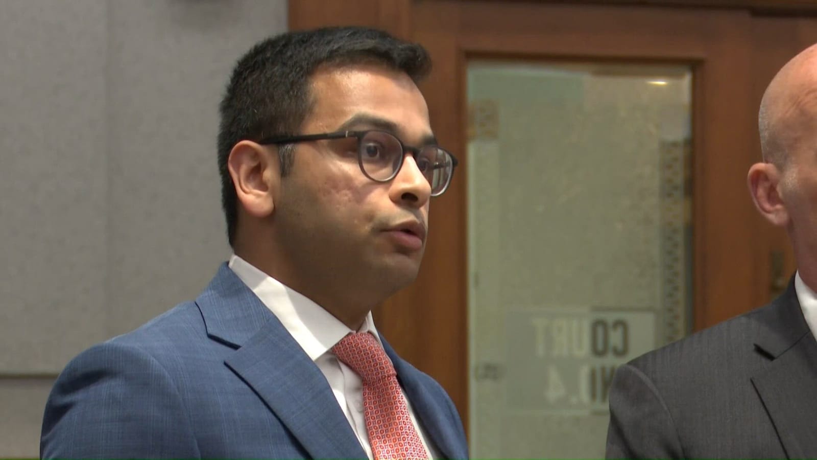 Indian-origin doctor in suit and glasses, potentially in a courtroom.