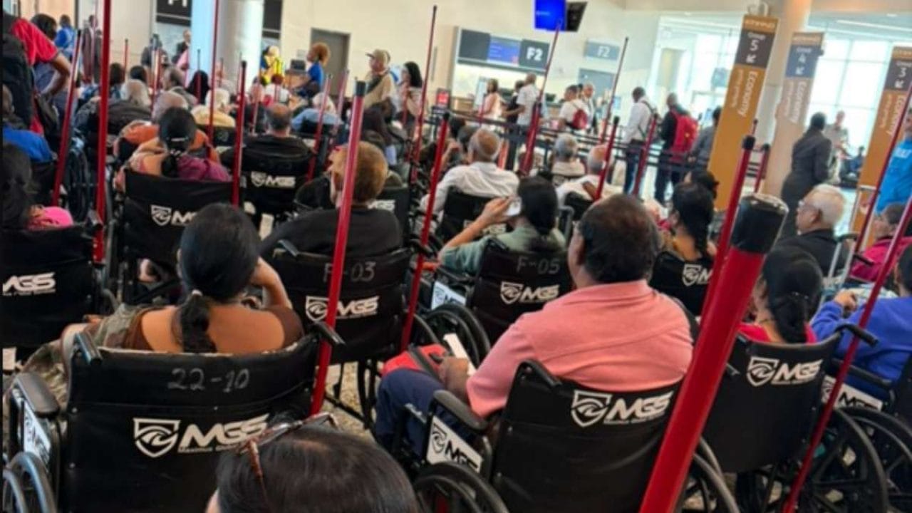 Airport scene with many people in wheelchairs, some with Indian flags on their chairs.