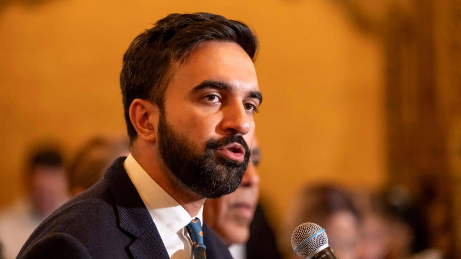 NYC lawmaker speaks at podium, related to politics and teacher aide bonuses