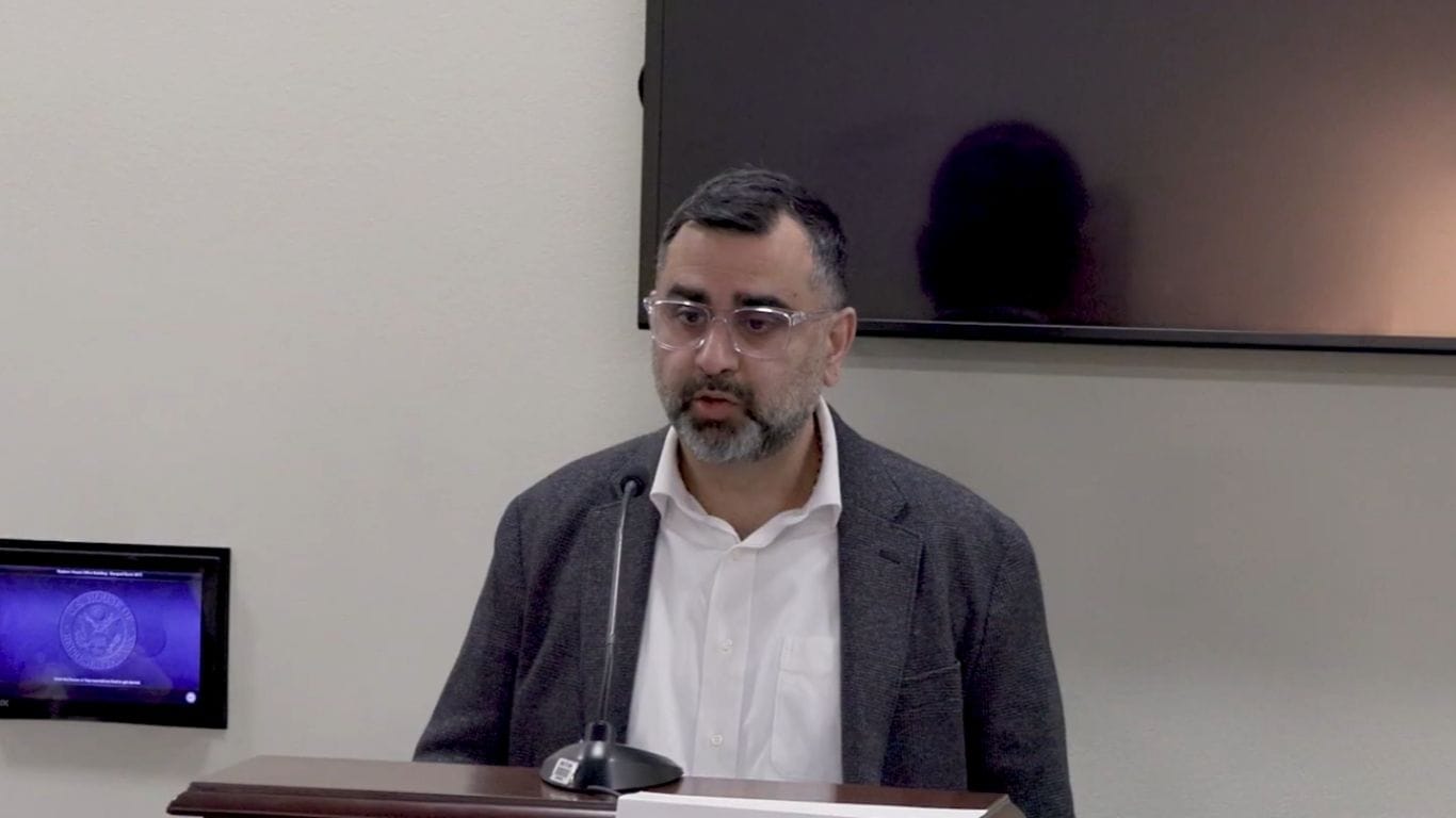 Bhaven Sampat, Bloomberg Professor, speaks at podium with Johns Hopkins logo on screen.