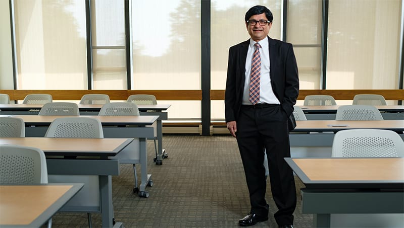 Indian American professor in a classroom, honored for tech sales research.