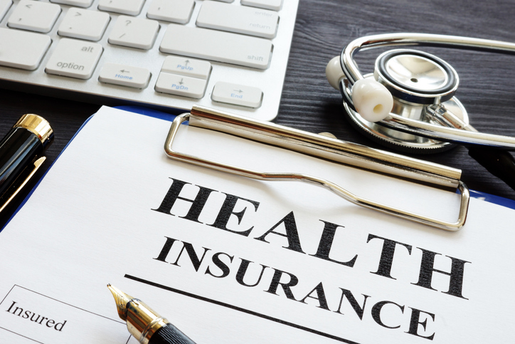 Health insurance document, stethoscope, keyboard, and pen - NRI guide for US health insurance.