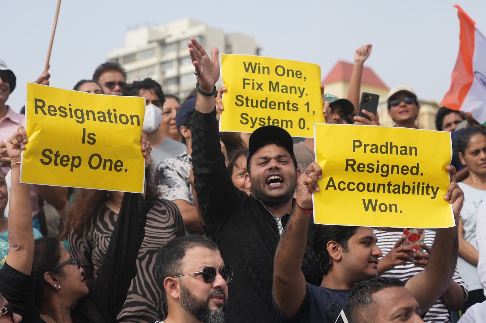 Protesters hold signs reading "Resignation Is Step One" and "Pradhan Resigned. Accountability Won.