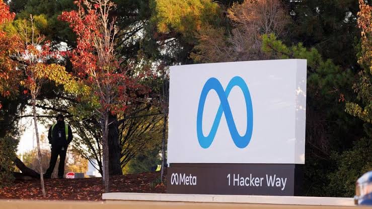 Meta logo sign with a person standing in front of it.