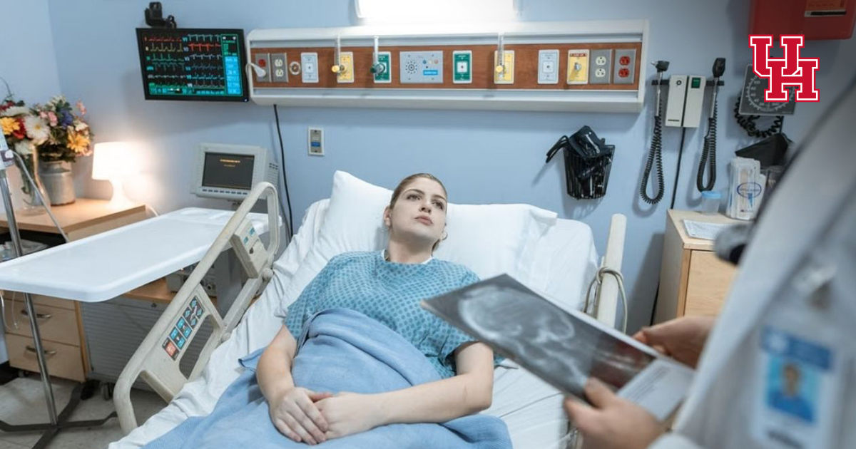 Patient in hospital bed with doctor reviewing X-ray